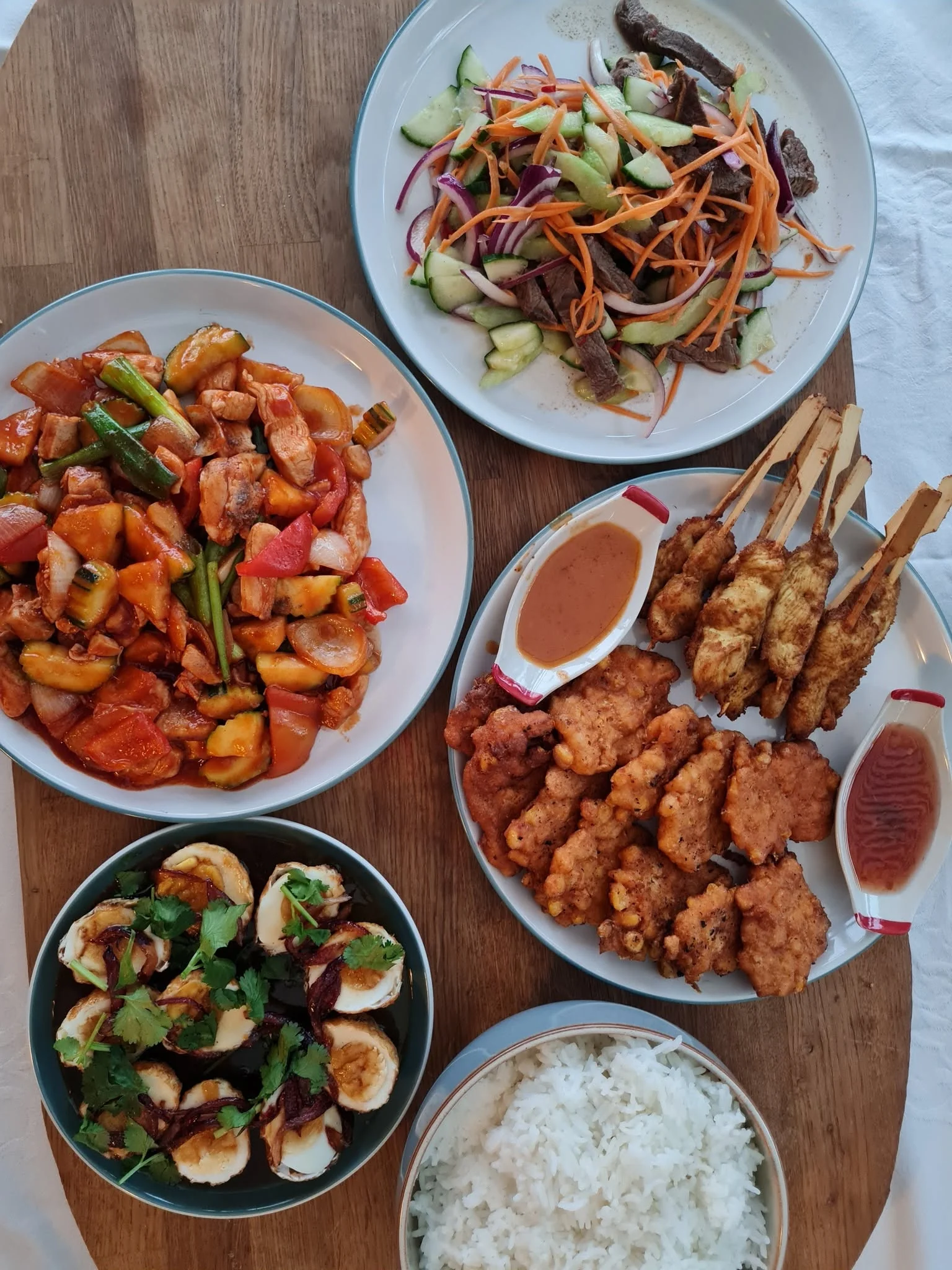 A spread of Thai dishes with salad, stir-fry, satay, rice and more, prepared by Kate